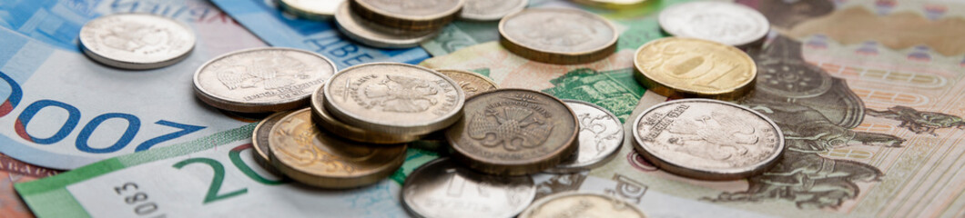 Paper rubles and coins are in a heap. Unstable exchange rate and crisis. Close-up. Panorama format.