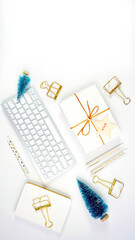 Christmas shopping desktop in modern gold and white theme with reindeer decoration, keyboard, gift and desktop accessories. Top view blog hero header creative composition flat lay.