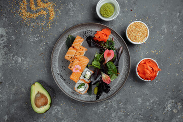 Delicious fresh sushi rolls with salmon and philadelphia cheese on gray plate on dark stone background. Traditional japanese seafood, healthy food concept