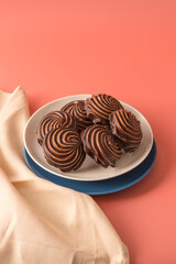 Traditional Russian vanilla marshmallows in chocolate glaze in white and blue plates on pink background. Colorful table and linen textiles