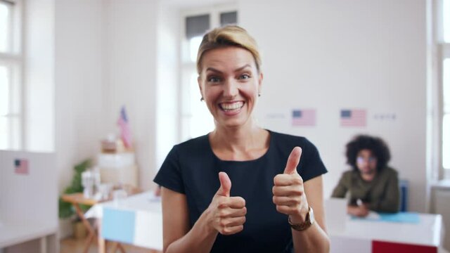 Portrait of happy woman voter with tumb up in polling place, usa elections concept.