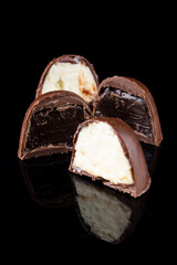 Chocolate truffle with delicious filling isolated on black background. Closeup photography.
