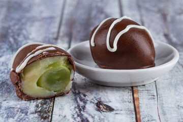 Chocolate truffle with green grape filling isolated on white background. Closeup photography.