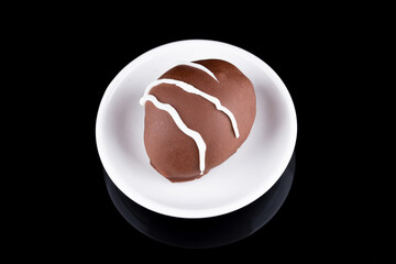 Chocolate truffle with green grape filling isolated on black background. Closeup photography.