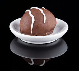 Chocolate truffle with green grape filling isolated on black background. Closeup photography.