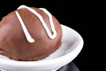 Chocolate truffle with green grape filling isolated on black background. Closeup photography.