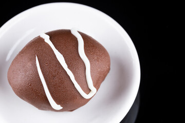 Chocolate truffle with green grape filling isolated on black background. Closeup photography.