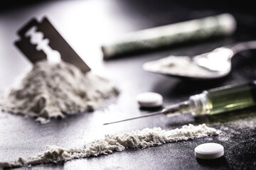 cocaine with rows, rows and lines of powder to be tested, with a drool blade beside it and syringes