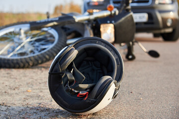 Photo of car, helmet and motorcycle on the road, the concept of road accidents.