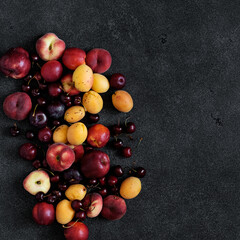Summer fruits and berries peach, plum, sweet cherry and apricots on a dark background