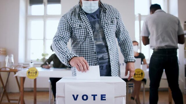 Mature man putting his vote in the ballot box, usa elections and coronavirus.