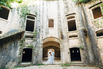 bride and groom are hugging in the ancient abandoned Arza fortress on the Mamula island