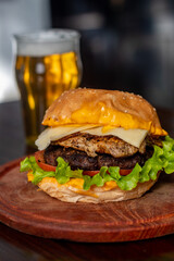 Big hamburger with a glass of beer in the background 