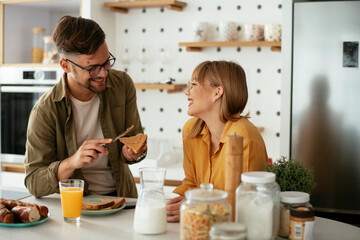 Young couple making sandwich at home. Loving couple enjoying in the kitchen