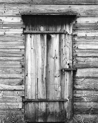 A vintage wood door with iron hinges padlocked shut on a abandoned building. The image was shot on analog film.