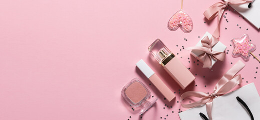 Long vide banner with set of decorative cosmetic, gift boxes and bags and shining decorations on pink pastel background.  Festive cosmetic sale banner. Christmas and Valentines Day present ideas.