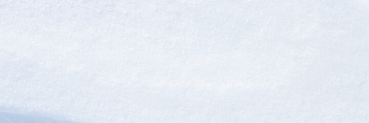 Beautiful winter background with snowy ground. Natural snow texture. Wind sculpted patterns on snow surface. Wide panoramic texture for background and design. Closeup top view with copy space.