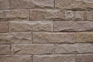 This unique photo shows the structure of a sandstone wall that stands outdoors. the individual stone slabs are very clearly visible with their pattern