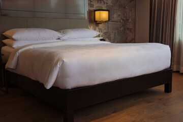 This unique photo shows a large bed standing in a hotel room. with bedside tables and beautiful lamps
