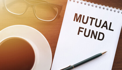 Mutual fund - text on paper with a cup of coffee and glasses on a wooden background in light. Business concept.