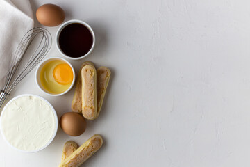 Ingredients for tiramisu, preparing tiramisu. Eggs, ladies finger cookies, mascarpone, coffee, whisk for beating eggs on a white background.