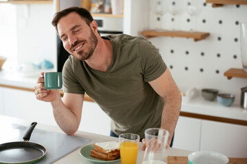 Fototapeta na wymiar Handsome man preparing breakfast at home. Young man enjoying in morning