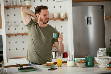 Handsome man preparing breakfast at home. Young man enjoying in morning
