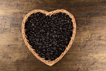 Roasted coffee beans in heart shaped basket. Top view.