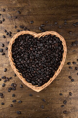 Roasted coffee beans in heart shaped basket. Top view.