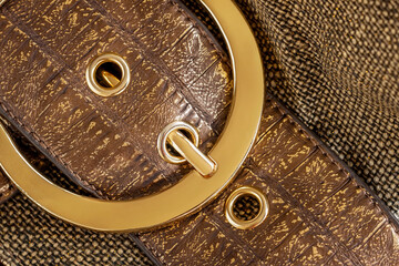 Part of leather handbag of brown color with golden bag buckle, metal detail close-up, background. No name, no logo