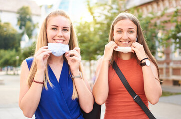 Young millennial friends with face mask after lockdown reopen - New normal friendship concept with...