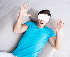 Young man wearing VR glasses relaxing on couch sofa