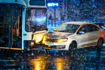 Traffic accident during snowstorm involving taxi car service and  public transport - trolleybus. Taxi car crashed, collision accident at city road. Road accident in blizzard, bad visibility