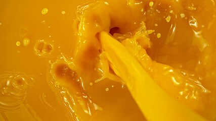 Naklejka na ściany i meble Freeze motion of pouring orange juice. Top view, close-up.