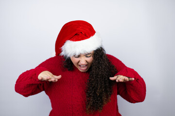 Young beautiful woman wearing a Santa hat over white background shouting and screaming loud down with hands on mouth
