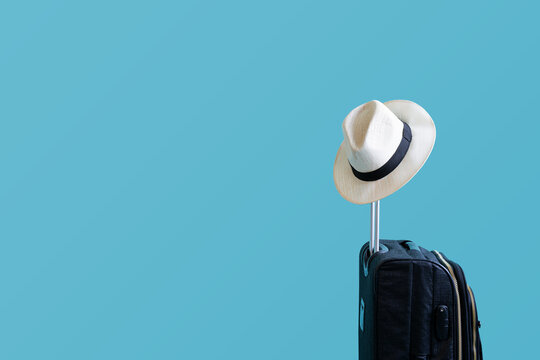 Vacaciones de verano, concepto de vacaciones y viajes. Maleta o bolsa de equipaje con sombrero para el sol sobre fondo azul para copiar el espacio.