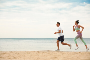 Couple running together on beach, space for text. Body training