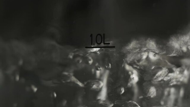 Close up footage of water boiling in pot. We see bubbles of boiling water with mark 1 liter