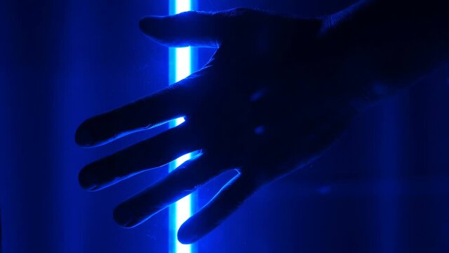 In the dark, with the blue illumination of the moving scanner lamp, the silhouette of the scanned male palm is visible for identification. Closeup