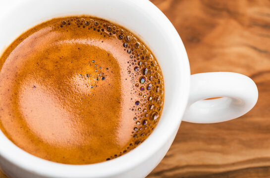 Cup of hot espresso coffee on wooden table.