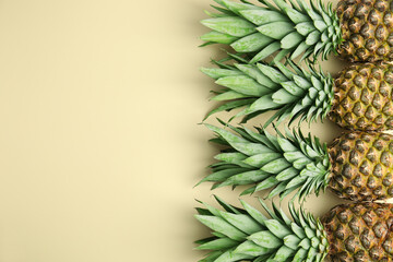 Fresh ripe juicy pineapples on beige background, flat lay. Space for text