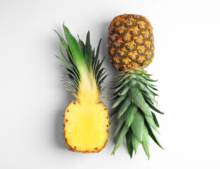 Whole and cut pineapples on white background, flat lay