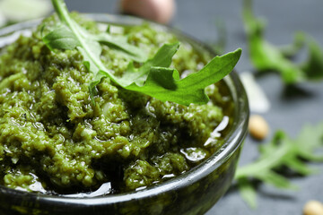 Bowl of tasty arugula pesto on table, closeup