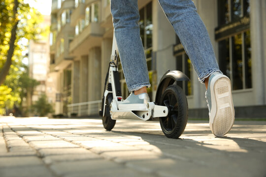 Woman riding electric kick scooter outdoors, closeup. Space for text