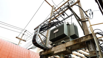 Power transformers and wires on the pole. Transformer with cable raft for large buildings On the background of the building roof and white sky. Close focus and select an object