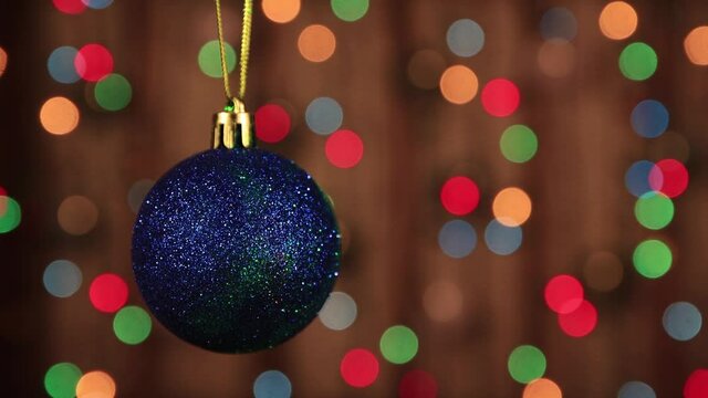 Decoration for the new year, a blue ball with a green ray in motion. Beautiful festive screensaver. Merry christmas congratulation. Abstract background of glowing garlands at night in the dark. 4K.