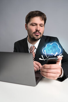 businessman using his smartphone with a virtual cloud above it on grey background