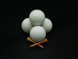 Stacked golf balls and tees on black background