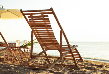 Wooden deck chairs and wicker table with cocktails on sandy beach. Summer vacation