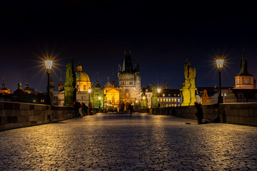 
old paved sidewalk with paving stones in memory of Charles Bridge from the 14th century in the center of Prague and in the background the old bridge tower at night in the Czech Republic